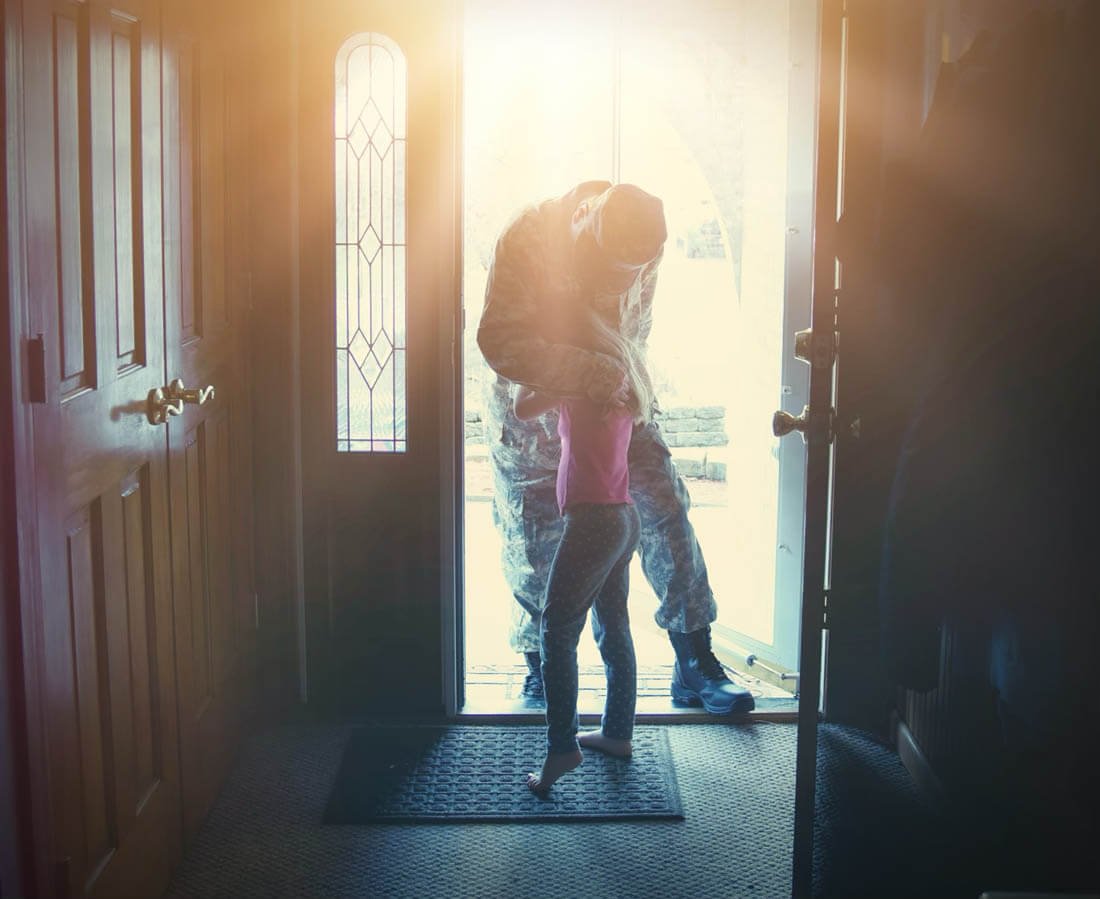 A soldier dad is coming home in the door and hugging his child for a love, family or reunited concept.